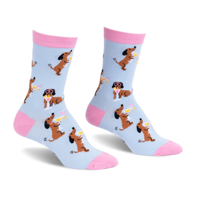Light blue crew socks with pink accents, featuring a pattern of brown dachshunds holding martinis and wearing sunglasses.