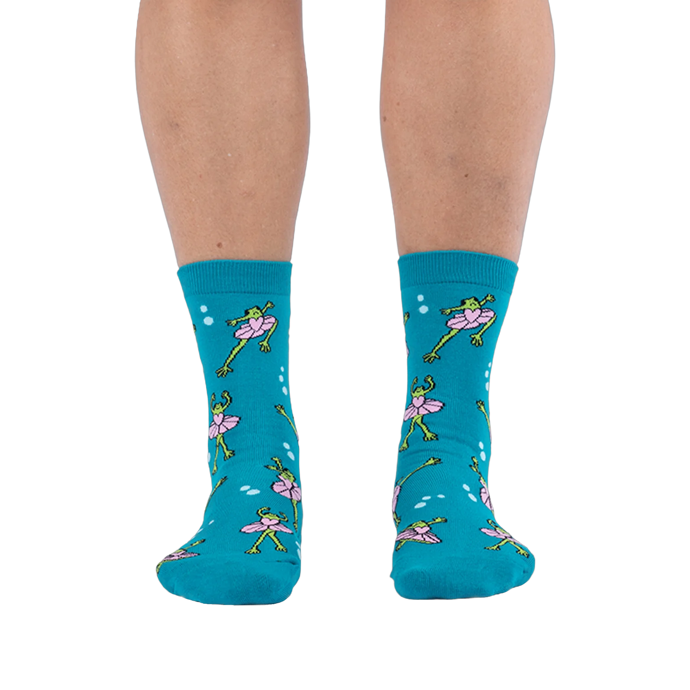 Front view of someone wearing teal crew socks featuring a pattern of green frogs in pink tutus on a black background.