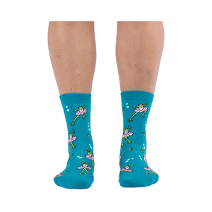 Front view of someone wearing teal crew socks featuring a pattern of green frogs in pink tutus on a black background.