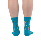 Back view of a person's calves wearing the teal ballet frog socks, showing the green frog and pink tutu design from behind.