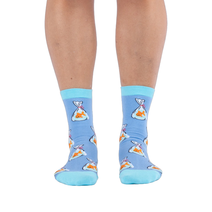 Front view of a person wearing light blue socks showing a pattern of orange goldfish in plastic bags and bright aqua cuffs.