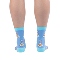 Back view of legs wearing light blue crew socks showing orange goldfish in plastic bags tied with red string and aqua heels.