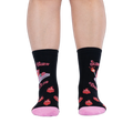 Front view of legs wearing black socks showing the pink book graphic, wrap-around text, lit matches, and flaming hearts.
