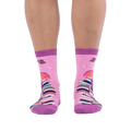 Front view of pink socks worn on legs, showing a tall stack of colorful books going up the shin with red roses at the top.