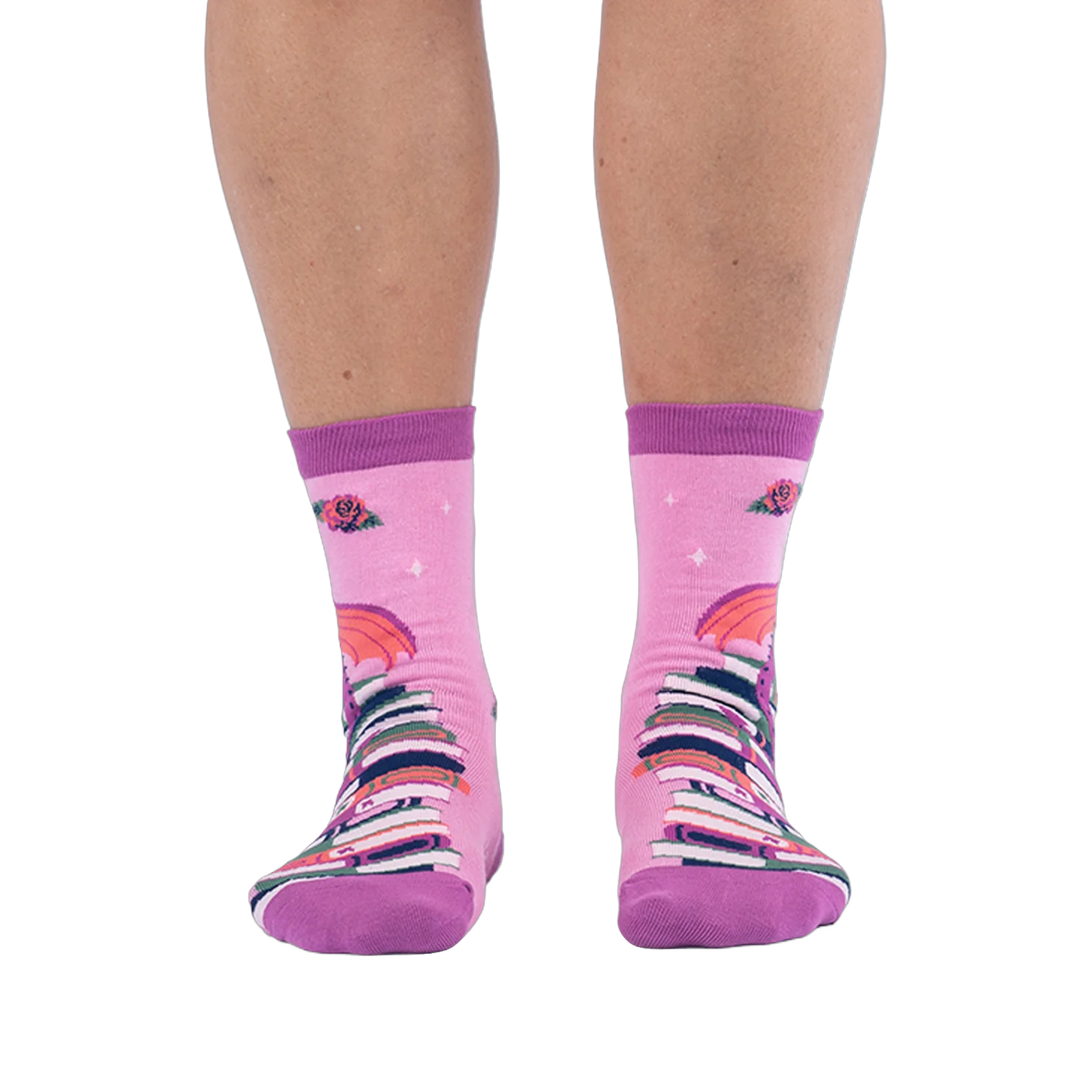 Front view of pink socks worn on legs, showing a tall stack of colorful books going up the shin with red roses at the top.