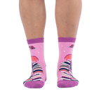 Front view of pink socks worn on legs, showing a tall stack of colorful books going up the shin with red roses at the top.