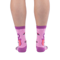 Back view of pink socks on legs, showing the back of a purple dragon with orange wings and scattered roses on the calves.