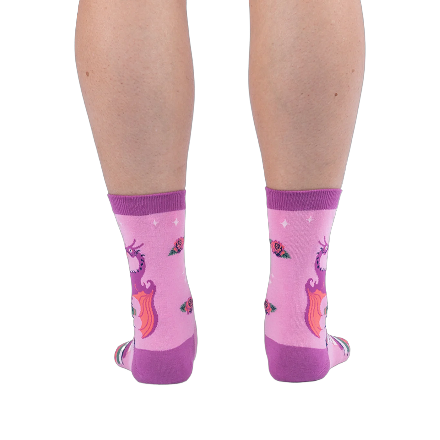 Back view of pink socks on legs, showing the back of a purple dragon with orange wings and scattered roses on the calves.