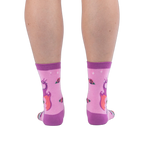 Back view of pink socks on legs, showing the back of a purple dragon with orange wings and scattered roses on the calves.