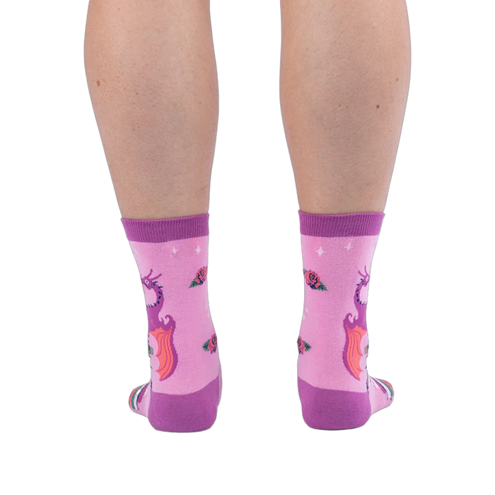 Back view of pink socks on legs, showing the back of a purple dragon with orange wings and scattered roses on the calves.