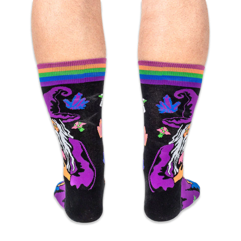 Back view of the socks being worn, displaying the back of the wizard's purple hat and glowing neon crystals on a black base.