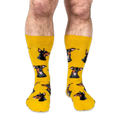 Front view of a person wearing yellow crew socks patterned with Doberman dog heads with big smiles and pink tongues.