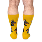 Back view of a person wearing bright yellow socks showing the profile of Doberman heads with classic black and tan markings.