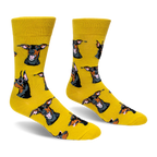A pair of bright yellow crew socks featuring a pattern of black and tan Doberman dog heads, some wearing pink sunglasses.