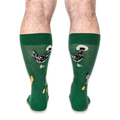Back view of a person wearing the green socks, highlighting black chickens with white fluffy head crests on the calves.