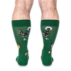 Back view of a person wearing the green socks, highlighting black chickens with white fluffy head crests on the calves.