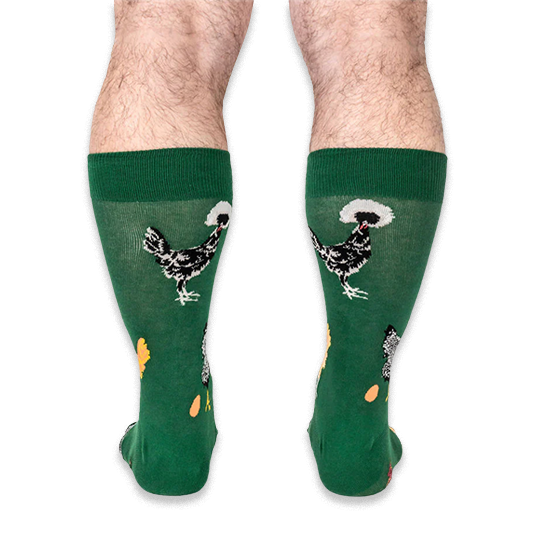 Back view of a person wearing the green socks, highlighting black chickens with white fluffy head crests on the calves.