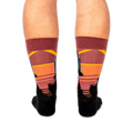 Back view of legs wearing space shuttle socks, showing the colorful striped sunset pattern wrapping around the calves.