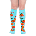 Front view of legs wearing bright turquoise knee-high socks patterned with bold red poppies and flying bumblebees.