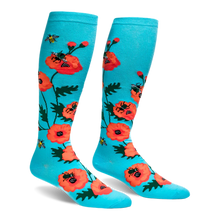 Bright turquoise knee-high socks featuring a pattern of large orange-red poppy flowers and flying yellow bumblebees.