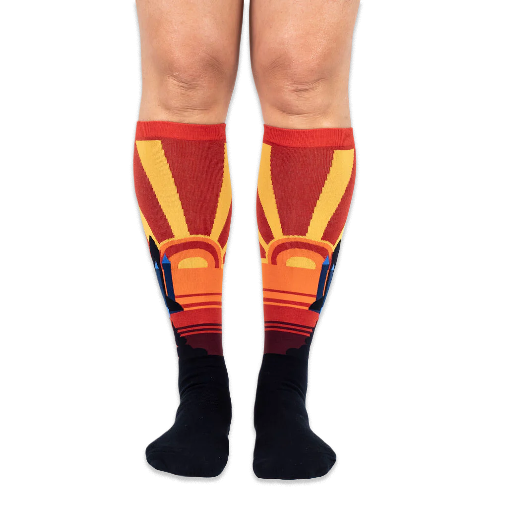Front view of someone wearing knee-high socks, showing large yellow sunbursts and space shuttles on the outer calves.