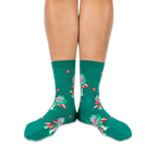 Someone wearing green crew socks with reading frogs and red mushrooms, viewed from the front against a black background.