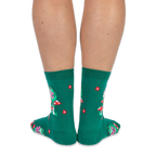 View from the back of someone wearing green crew socks featuring a pattern of red flowers and green frogs on mushrooms.