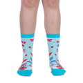 Front view of a person wearing light blue crew socks with teal trim and Thrifty B*tch text below the cuff.