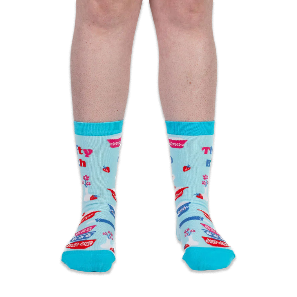 Front view of a person wearing light blue crew socks with teal trim and Thrifty B*tch text below the cuff.