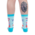 Back view of a person wearing light blue retro kitchen socks. The person has a black cat cameo tattoo on their calf.