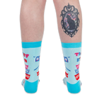Back view of a person wearing light blue retro kitchen socks. The person has a black cat cameo tattoo on their calf.