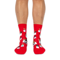 Front view of someone wearing red socks, showing small dogs in white tote bags with teal blue hearts and bows on the shins.