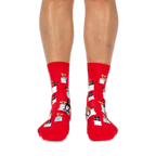 Front view of someone wearing red socks, showing small dogs in white tote bags with teal blue hearts and bows on the shins.