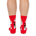 Back view of a person wearing red crew socks with a pattern of dogs in bags, showing the heel and calf design.