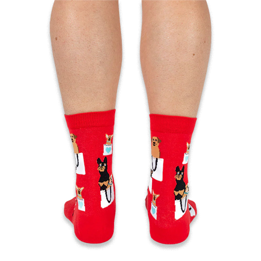 Back view of a person wearing red crew socks with a pattern of dogs in bags, showing the heel and calf design.