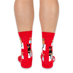 Back view of a person wearing red crew socks with a pattern of dogs in bags, showing the heel and calf design.