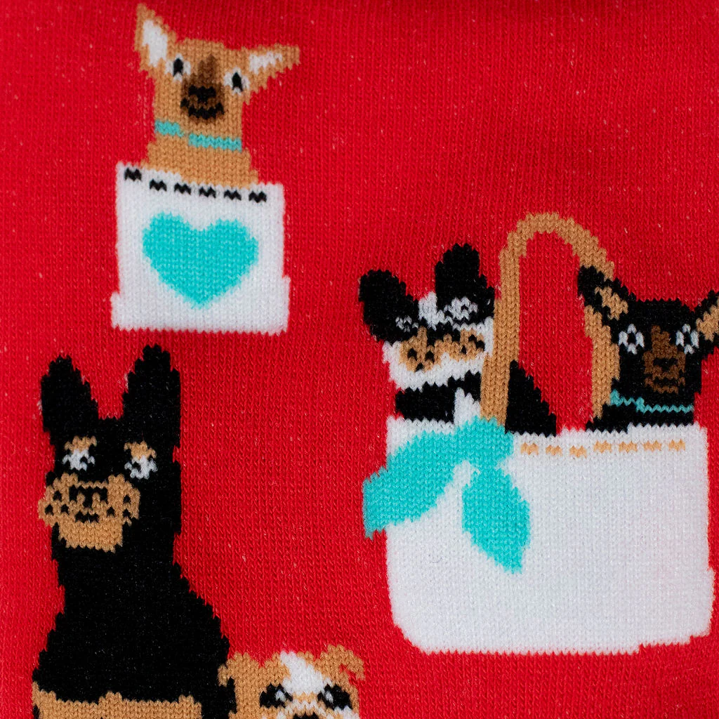 Close-up of red knit sock fabric showing black and tan dogs sitting inside white bags decorated with teal blue details.