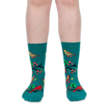Front view of a person's lower legs wearing teal crew socks with a pattern of birds, black branches, and pink flowers.