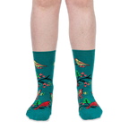 Front view of a person's lower legs wearing teal crew socks with a pattern of birds, black branches, and pink flowers.