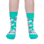 Front view of someone wearing bright teal crew socks with grey seal pups on icebergs against a black background.