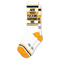 White crew socks featuring black and yellow stripes, yellow heels, and bold black text reading ARE YOU FUCKING KIDDING ME.