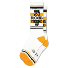 White crew socks featuring black and yellow stripes, yellow heels, and bold black text reading ARE YOU FUCKING KIDDING ME.