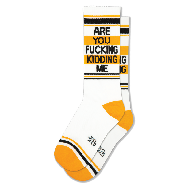 White crew socks featuring black and yellow stripes, yellow heels, and bold black text reading ARE YOU FUCKING KIDDING ME.