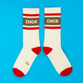 Two cream crew socks laid flat on a blue background, each with a brown "DICK" band and red accents.