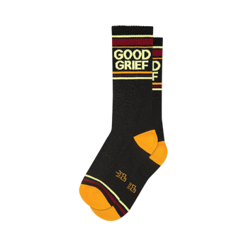 A folded pair of black crew socks featuring 'Good Grief' text, orange toe and heel, and burgundy, gold, and cream stripes.