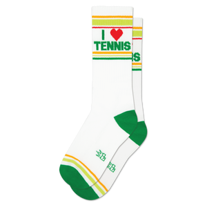 Pair of white crew socks with green and yellow-orange cuff stripes. Features 'I ❤️ TENNIS' text with a red heart. Green heels and toes.