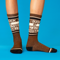 A person's legs wearing brown crew socks with "I Suck At Fantasy Football" text, on a blue background.