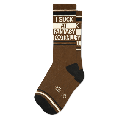 A single brown crew sock with black toes and heels. Features "I SUCK AT FANTASY FOOTBALL" text on a white band.