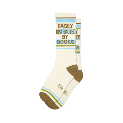 Pair of cream crew socks with 'Easily Distracted By Books' in green text, horizontal brown, blue, and green stripes.