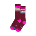 Pair of burgundy crew socks with "BADASS GRANDMA" in white, hot pink toes, and horizontal pink and blue stripes on the cuff.